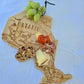Ontario Map-shaped cutting board with prosciutto, cheese, and grapes on a white plate.