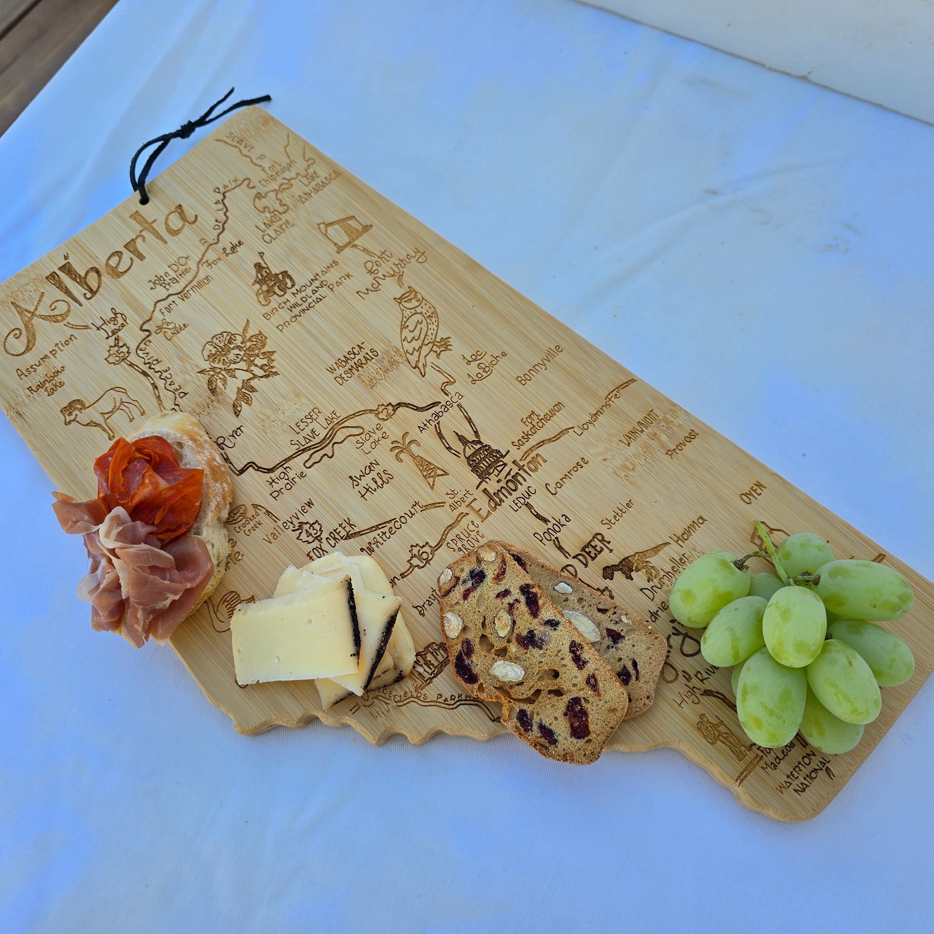 Wooden board with cheese, crackers, and grapes on a white surface